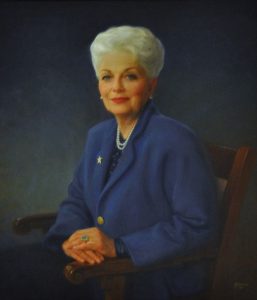 Portrait of former Texas Governor Ann Richards in a blue suit sitting in a chair