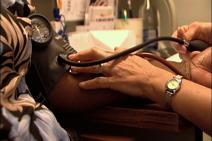 A patient has her blood pressure taken at the clinic in Jonestown, Bodies and Souls, 2005. Screenshot by Southern Spaces. A patient has her blood pressure taken at the clinic in Jonestown, Bodies and Souls, 2005. Screenshot by Southern Spaces.