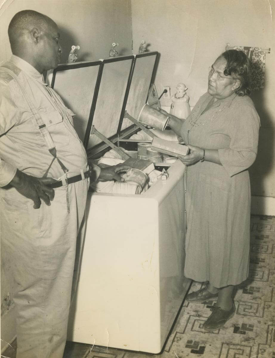 A sepia-toned photograph showing Edward Scott Sr. and Juanita Scott standing at a freezer