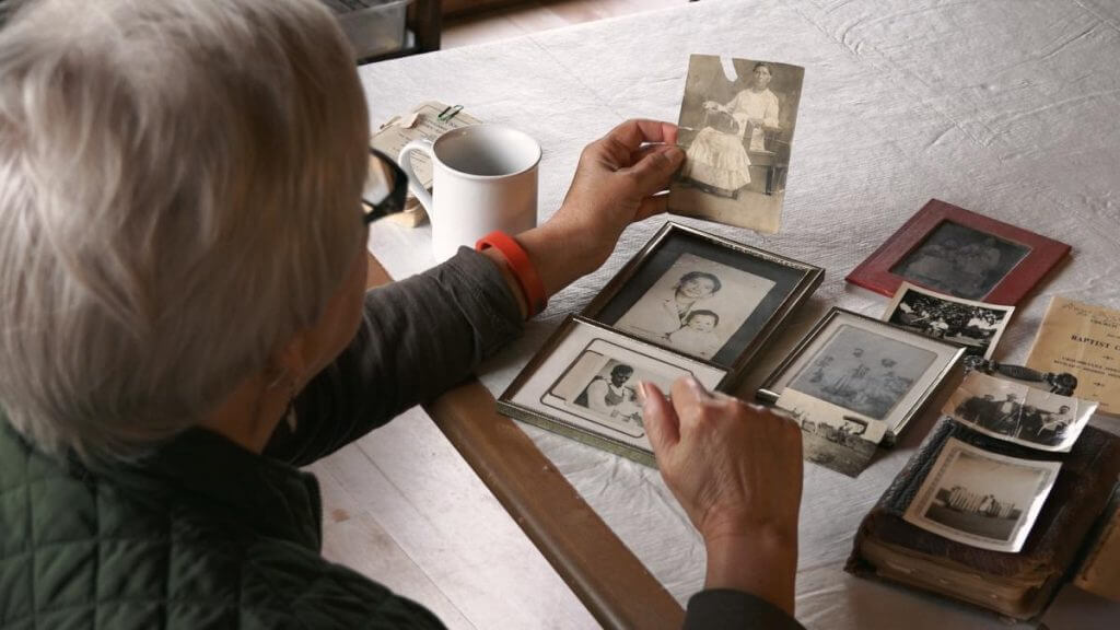 Rosemary McCombs Maxey looks at family photographs, Dustin, Oklahoma, 2015. Screenshot from Hearing the Call courtesy of Southern Spaces.