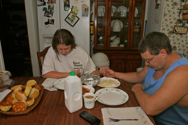 Surface miner and his wife bow heads in prayer before breakfast. This miner's father succumbed to black lung disease at 57. Peck's Mill, WV, 2005.