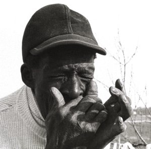 William Grant plays the harmonica, eyes closed tightly.