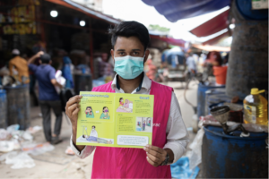 A project volunteer showing a Covid-19 info card, Bangladesh. Photograph courtesy of Abdullah Al Kafi.