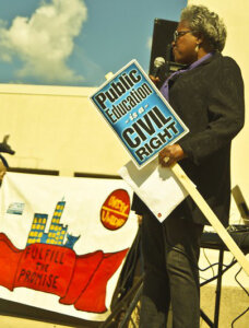 Political strategist Donna Brazile speaking at the Fulfill the Promise of Brown v. Board of Education March in Milwaukee, Wisconsin, May 17, 2014. Photograph by Flickr User Joe Brusky. Creative Commons License CC BY-NC 2.0 DEED. Original cropped by Southern Spaces.
