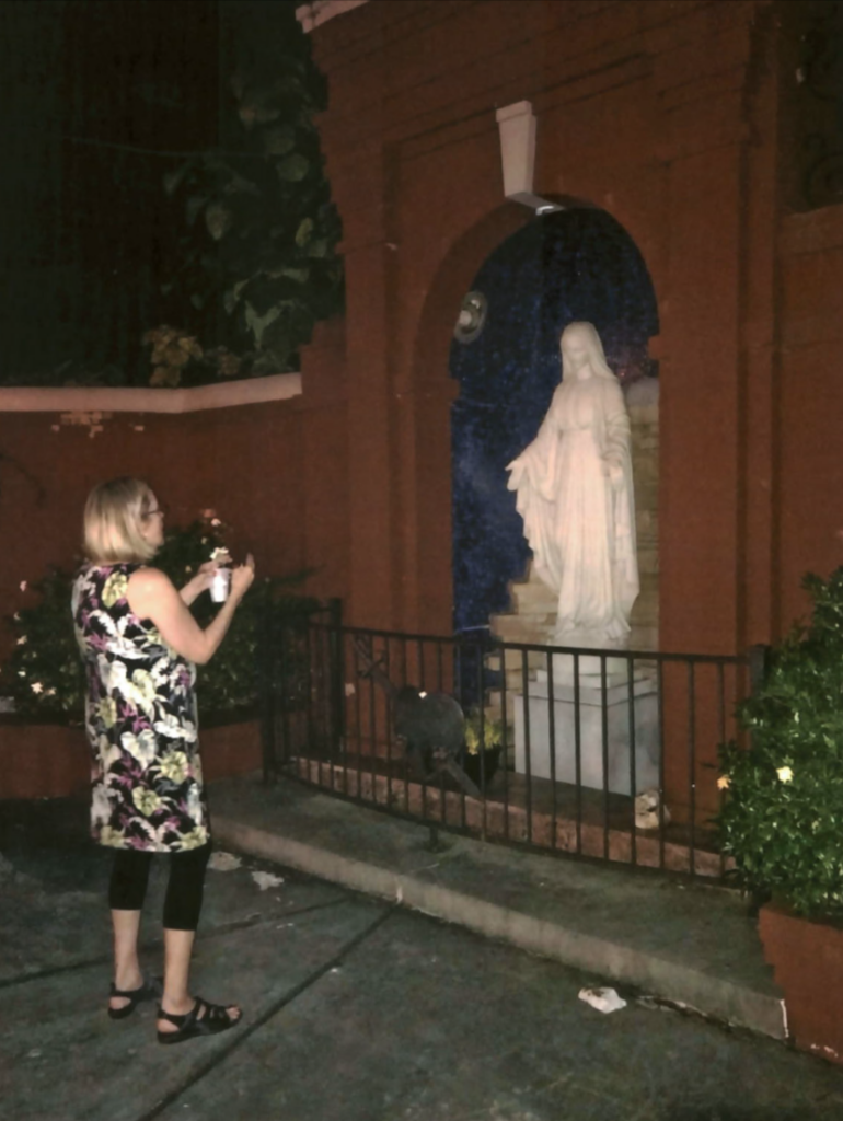 Ruth Burks takes a photograph of a statue of the Virgin Mary.
