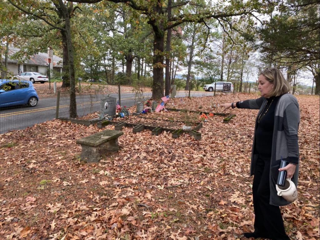 Ruth Burks stands in the cemetery and points towards an option for the monument's placement.