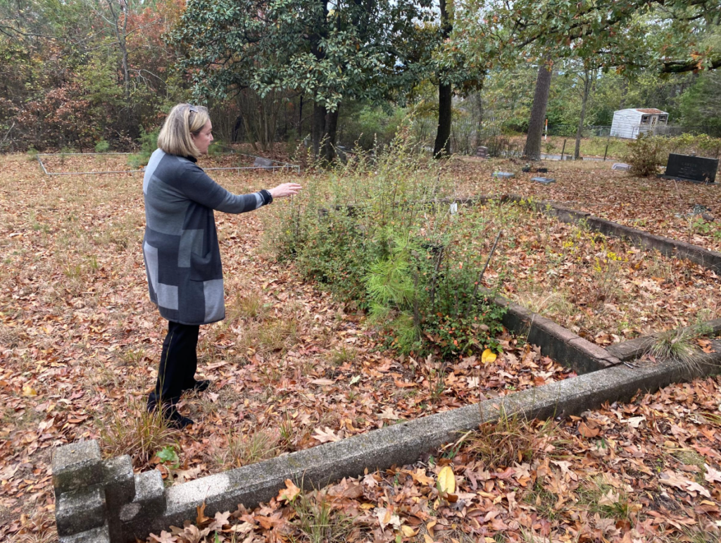 Ruth Burks stands in the cemetery and points towards an option for the monument's placement.
