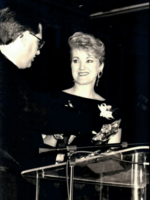 Ruth Burks, dressed in elegant attire, is presented with an award.